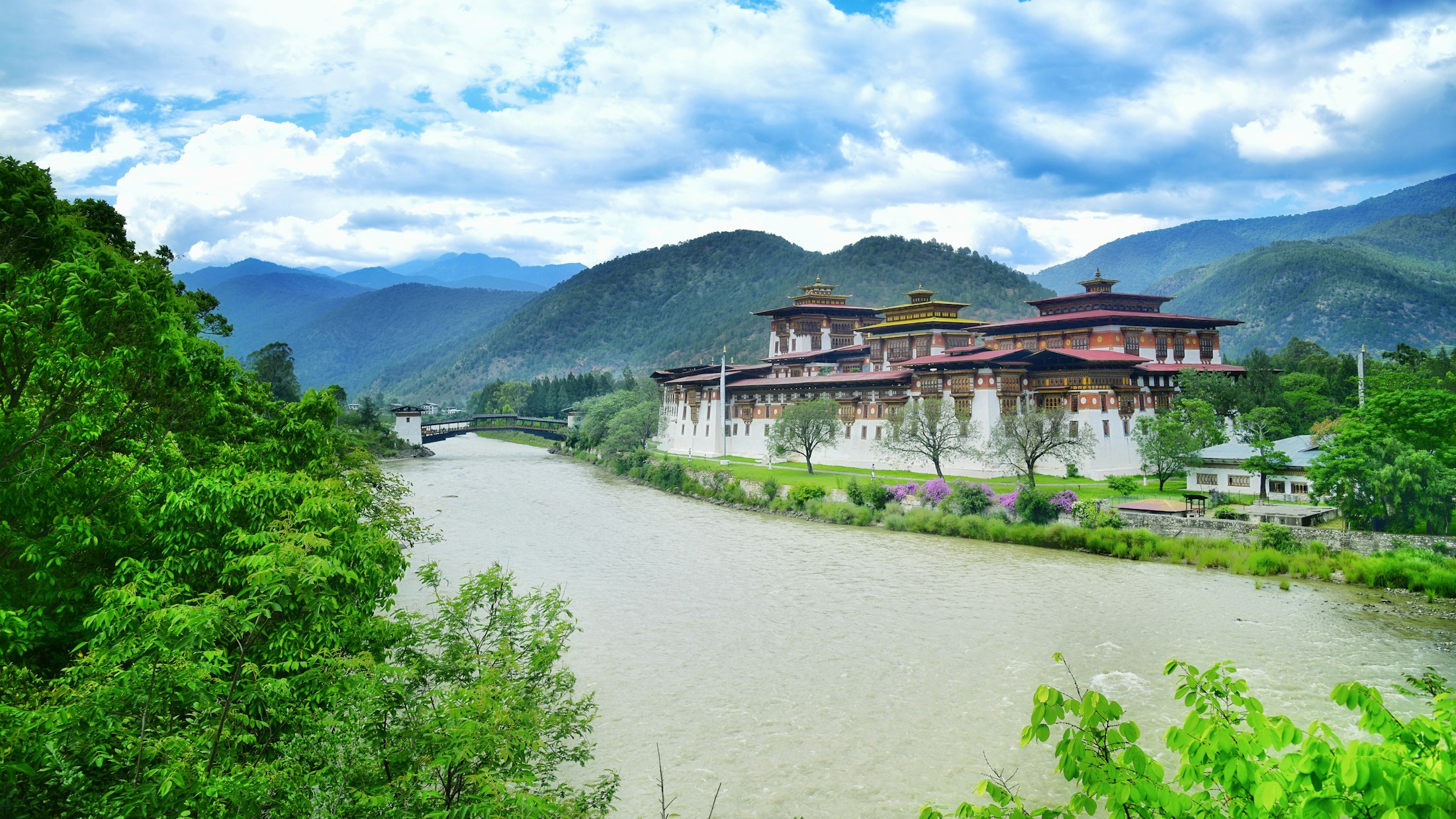 Punakha Dzong sits beside a wide river with green Bhutanese hills beyond