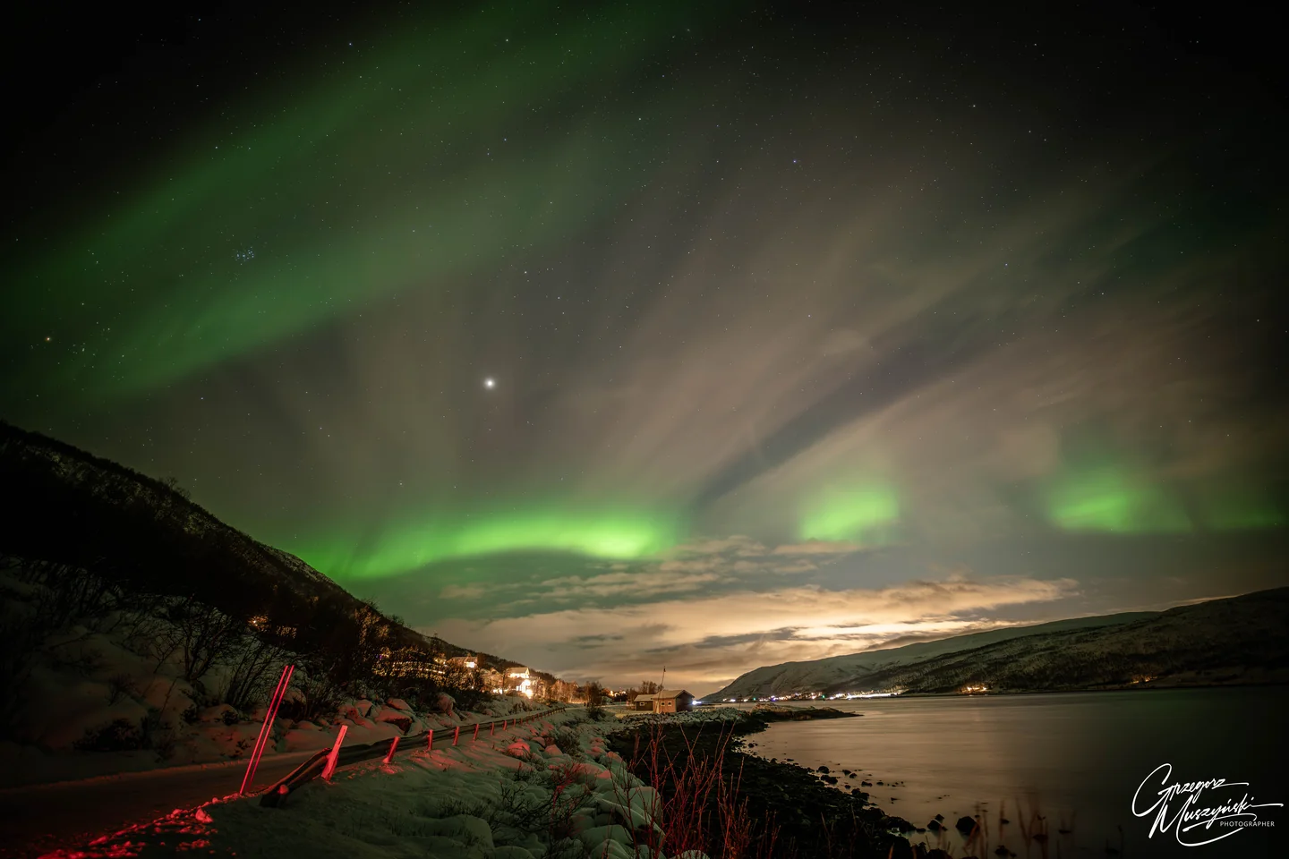 Aurora above a snowy coastal landscape near Tromsø, Norway