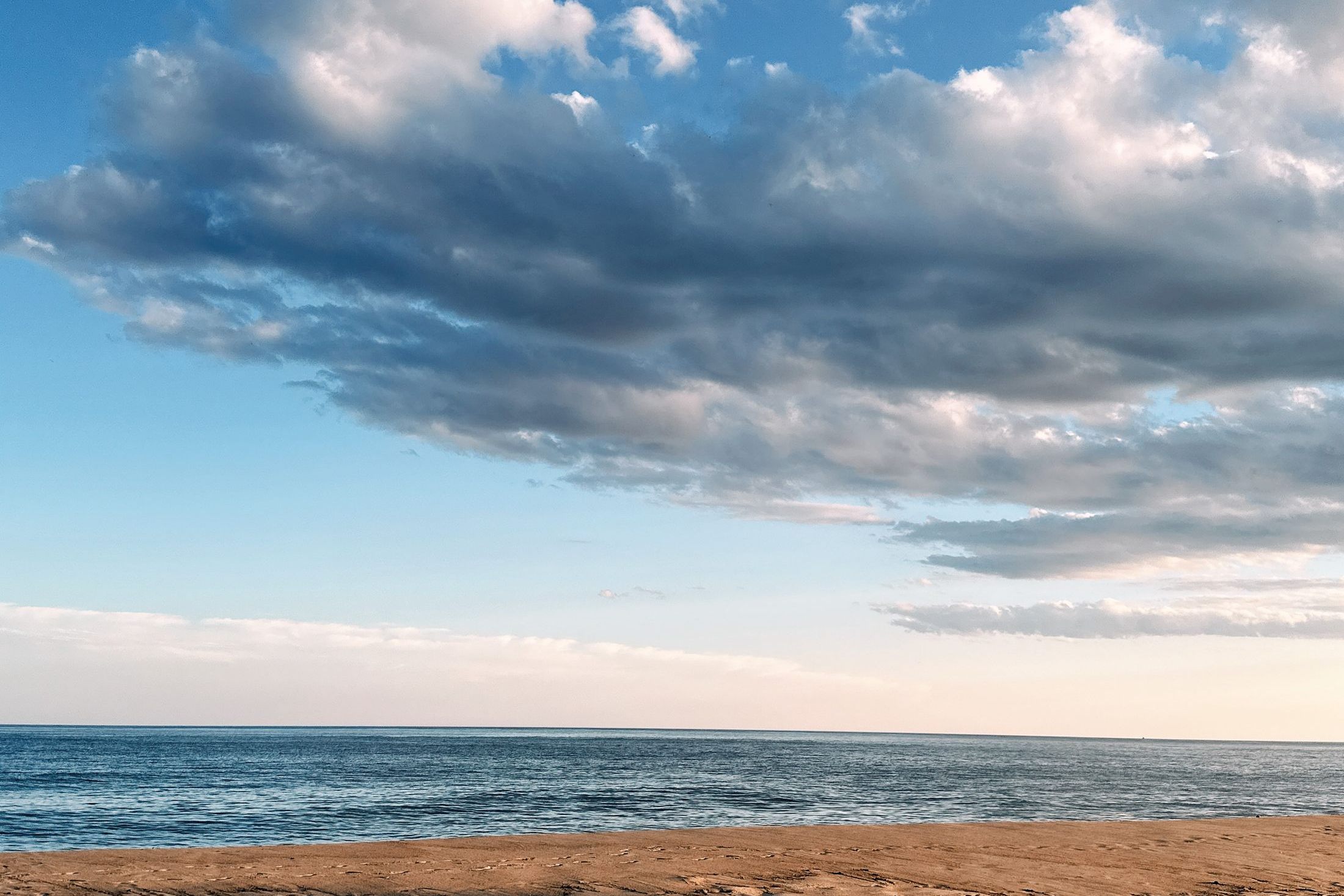 A quiet Hampton Bays beach reflects soft sunset color along calm water