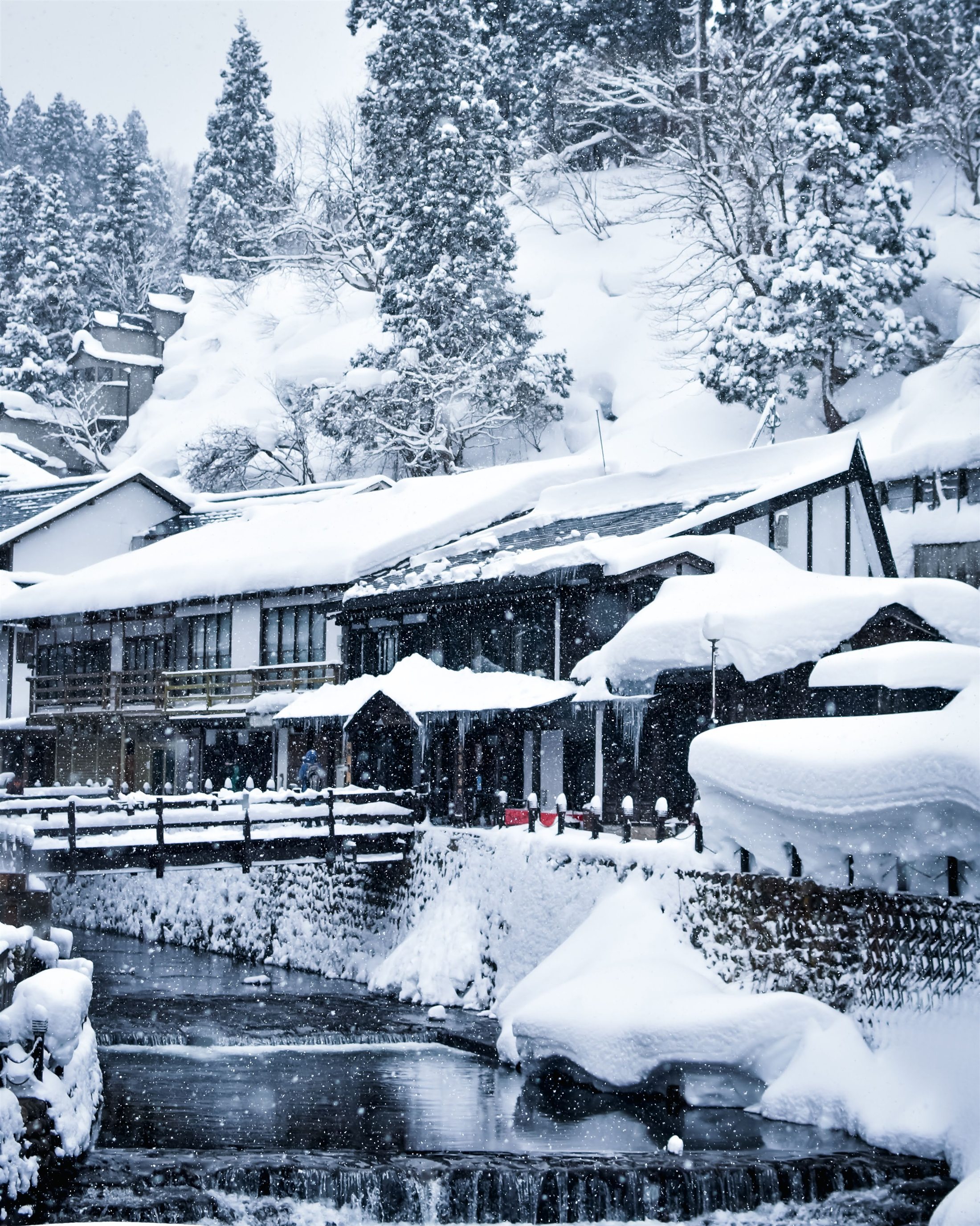Snow-covered Japanese village beside a narrow winter stream