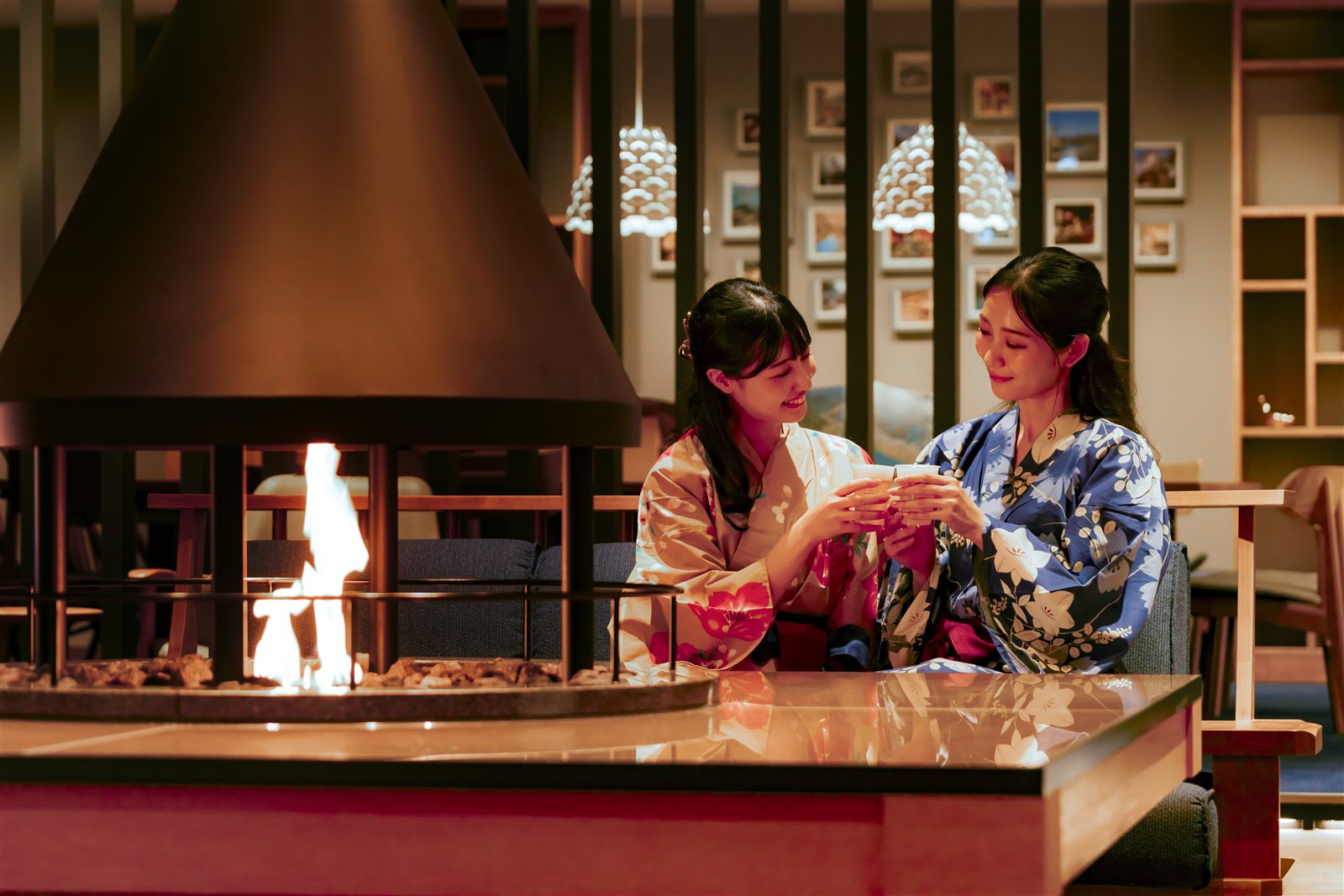 Two models wearing yukata beside the fireplace in Premium Kinosaki’s hotel lounge