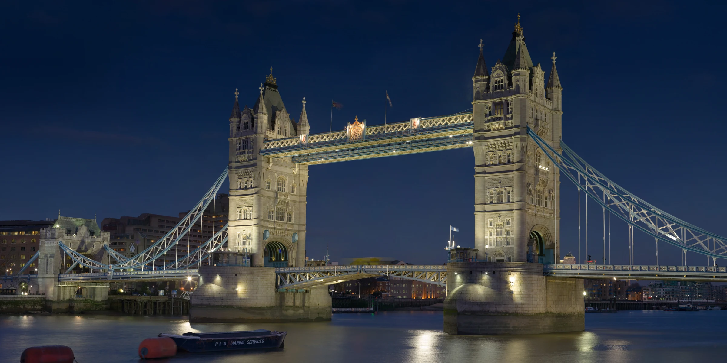 Illuminated stone towers and upper walkway of Tower Bridge over the Thames in London at dusk